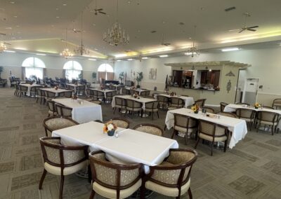 Spacious, elegant dining room at Northfield Retirement Communities with chandeliers, large windows, and restaurant-style seating.